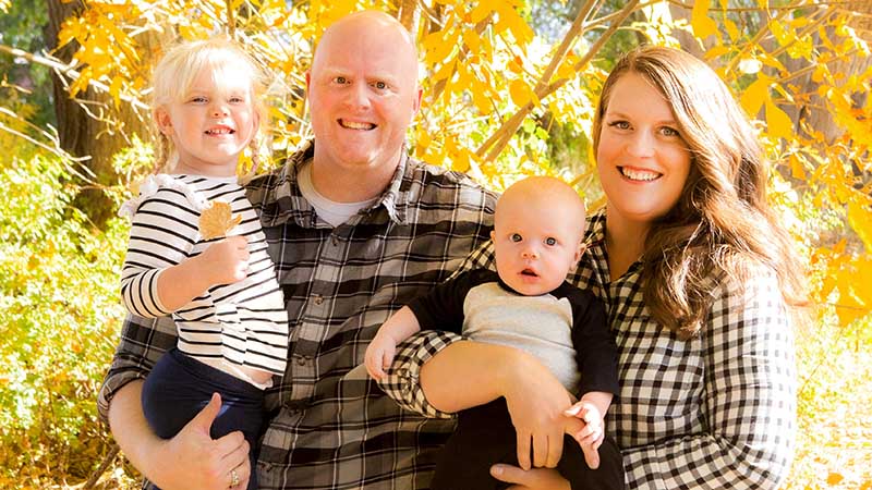 family standing outside in front of tree with fall colors