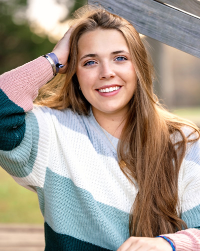 Trinity Winert in a striped sweater poses for a photo outdoors on a sunny day