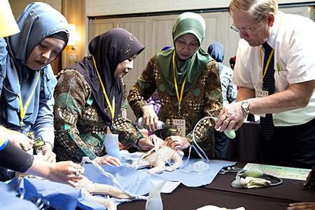 Doctor Dennis Hughes conducts a progress review with a small group of midwives