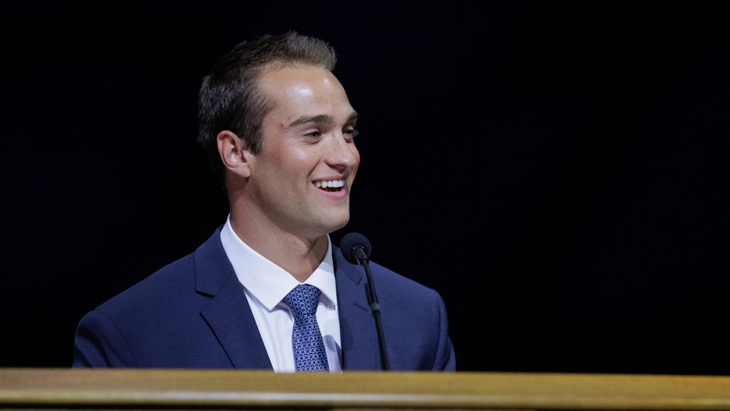 Chase Roberts in a suit and tie speaking at a BYU devotional