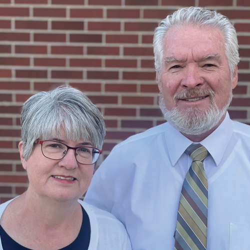 Kerry and Cynthia Belnap pose for a photo outside in front of a brick wall