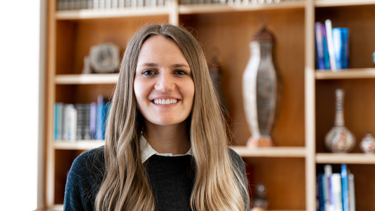 Young woman with long hair in front of bookshelf