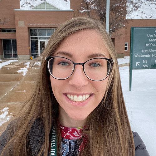 Headshot of young woman BYU student in front of campus building with snow on the ground.