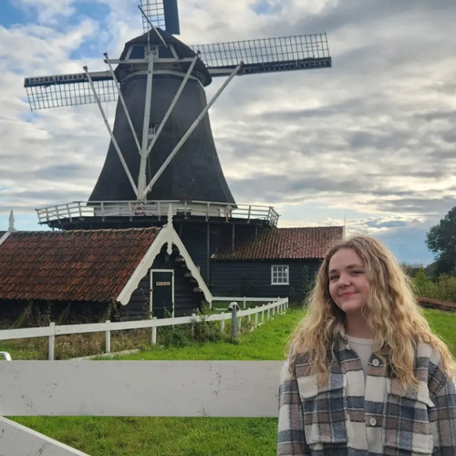 Sister Katherine Welton smiling and standing in front of a windmill.