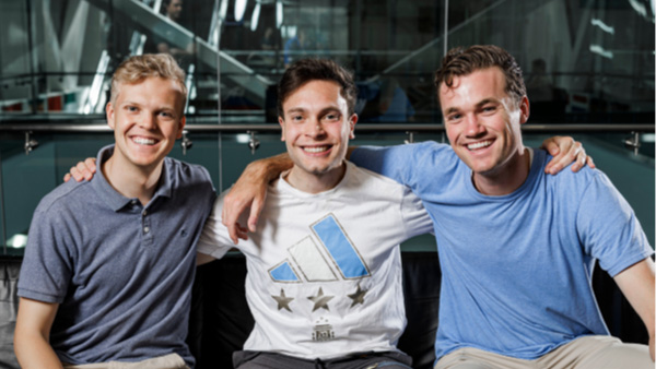 Brice Douglas, Santiago Gomez-Paz and Daniel Jones sitting together and smiling in the Tanner Building. 