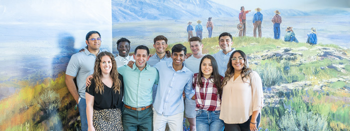 A group of Ensign College in front of a mural painting