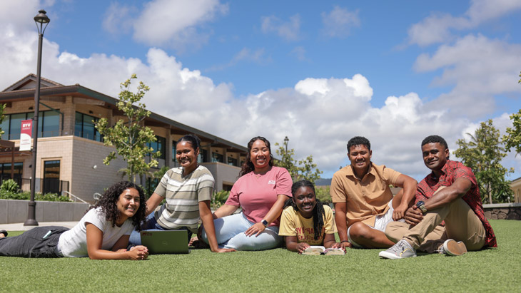 A group of BYU-Hawaii students gathered to study outdoors, smiling at camera