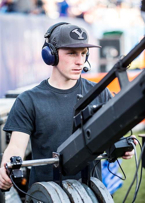 man operating a camera at a BYU football game