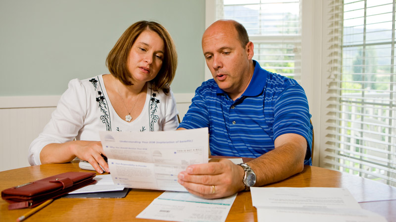 A married couple sitting at their kitchen table looking at paperwork