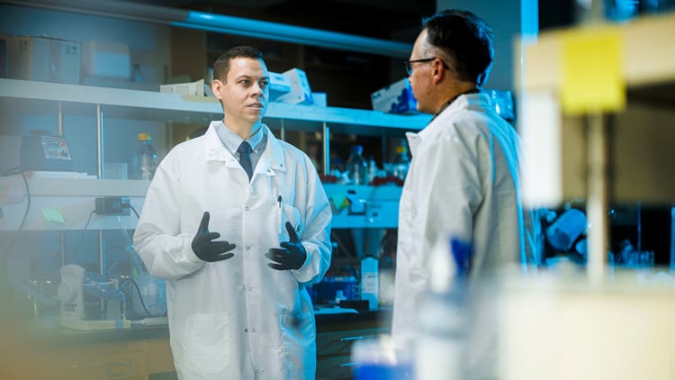 Two men wearing lab coats in a biochemistry research lab at BYU.