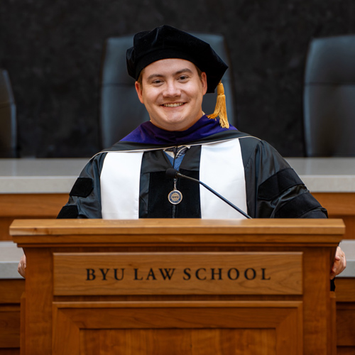 William Emery in his graduation cap and gown giving a speech