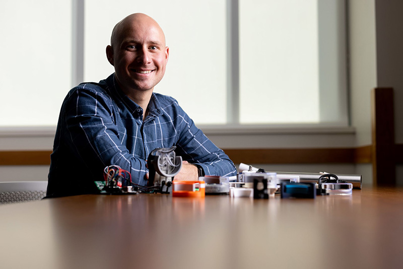 Male student seated at table with electronic parts