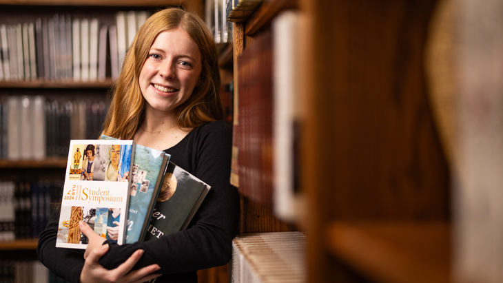 BYU student Emma Clark smiling in a library holding books