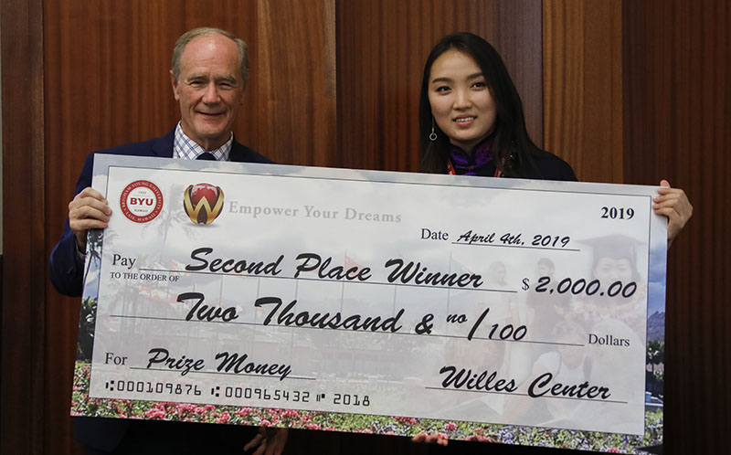 A Mongolian woman being presented with a large check.