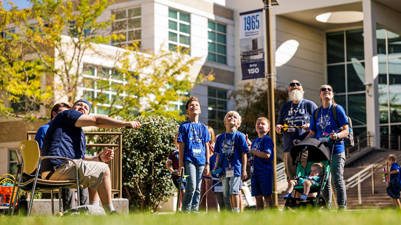 A family watches a demonstration outdoors on campus