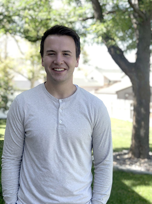 male student outdoors by a tree