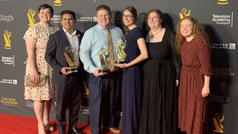 A group of people with awards at an formal awards ceremony.