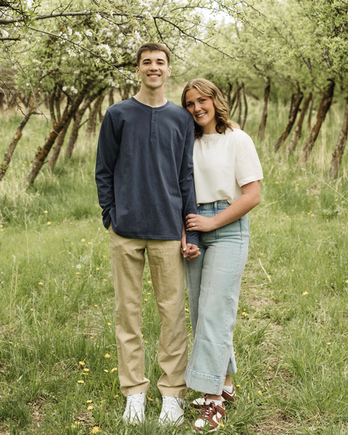 Kenton and Trevian Frederick, holding hands and smiling in an orchard)
